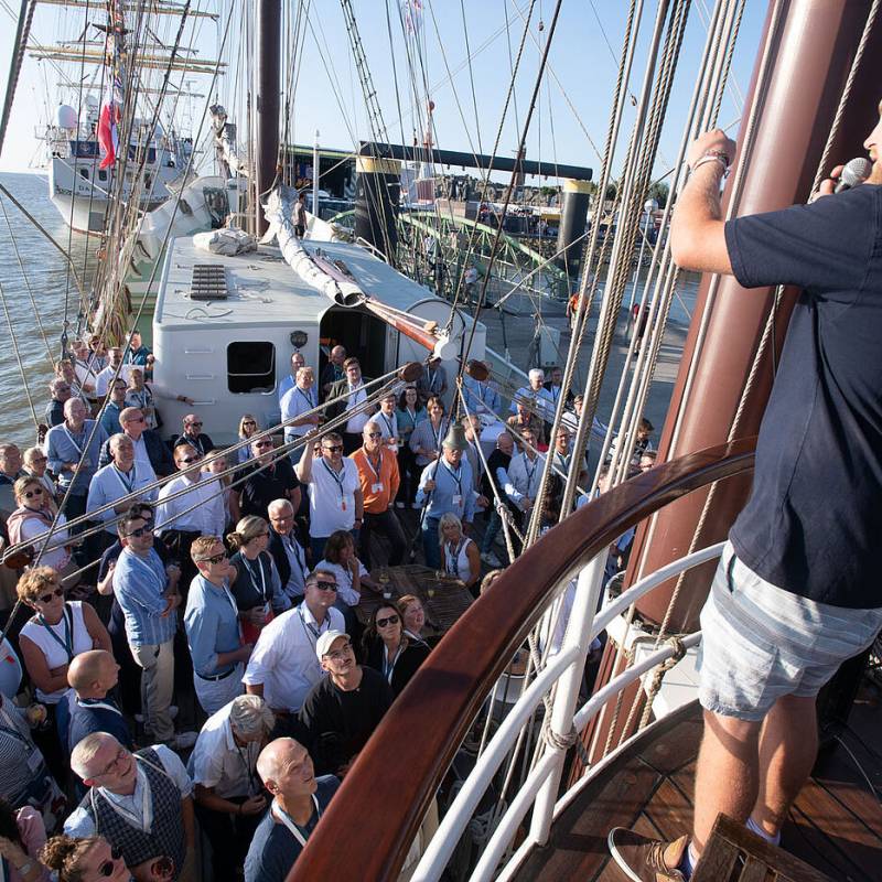 Gespannte Zuschauerschaft lauscht einem Vortrag auf einem Segelschiff